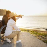 un hombre en silla de ruedas contemplando una puesta de sol junto a su pareja