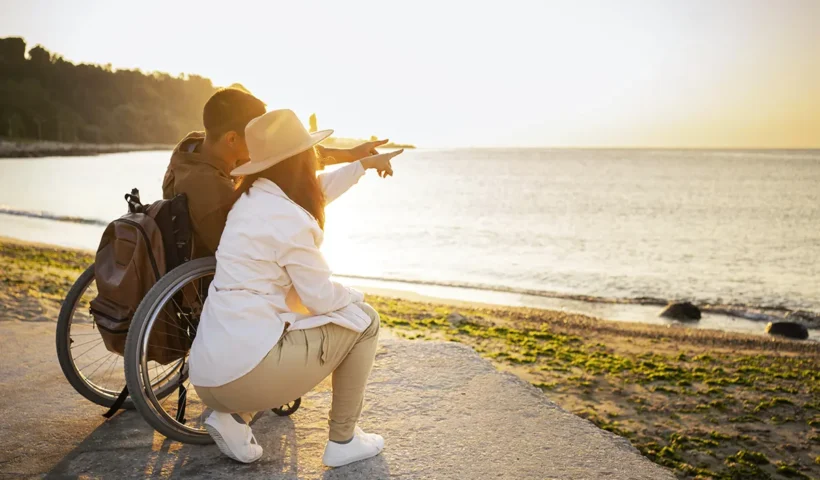 un hombre en silla de ruedas contemplando una puesta de sol junto a su pareja