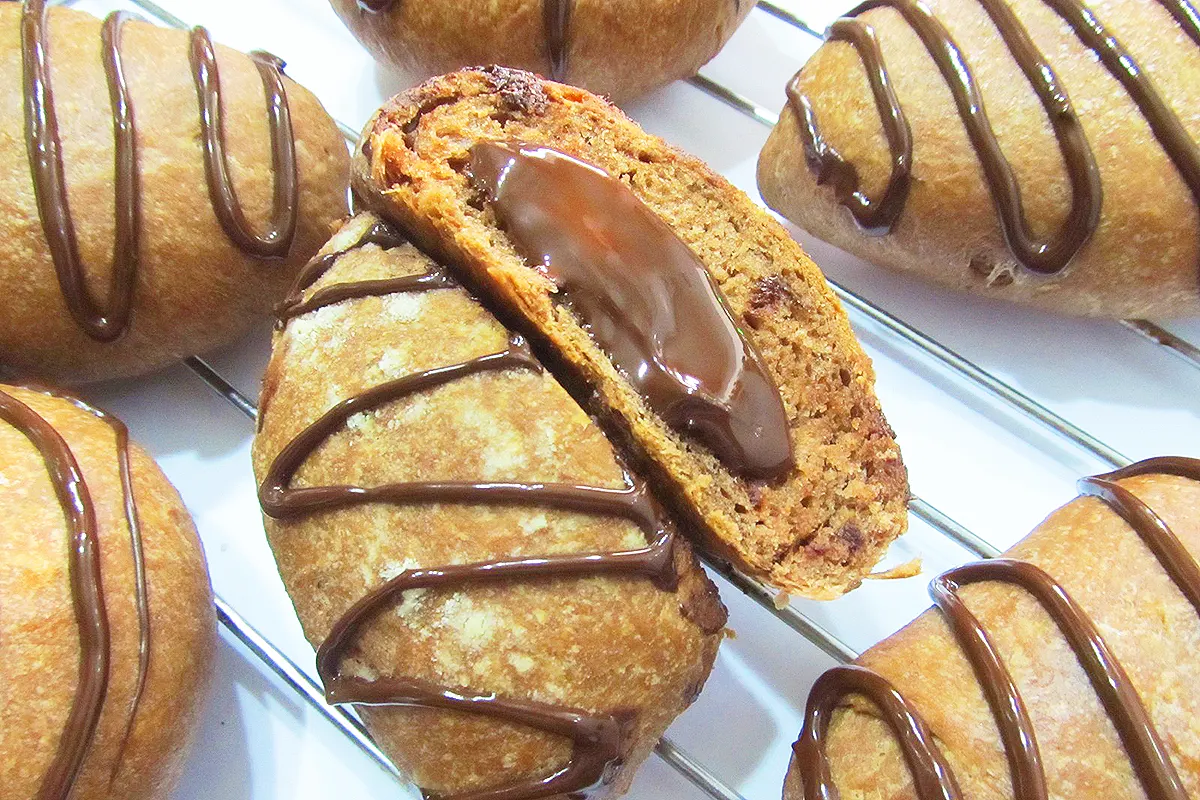 varios bollos hechos con harina y cacao y decorados, uno de ellos partido y mostrando en el interior su relleno de chocolate