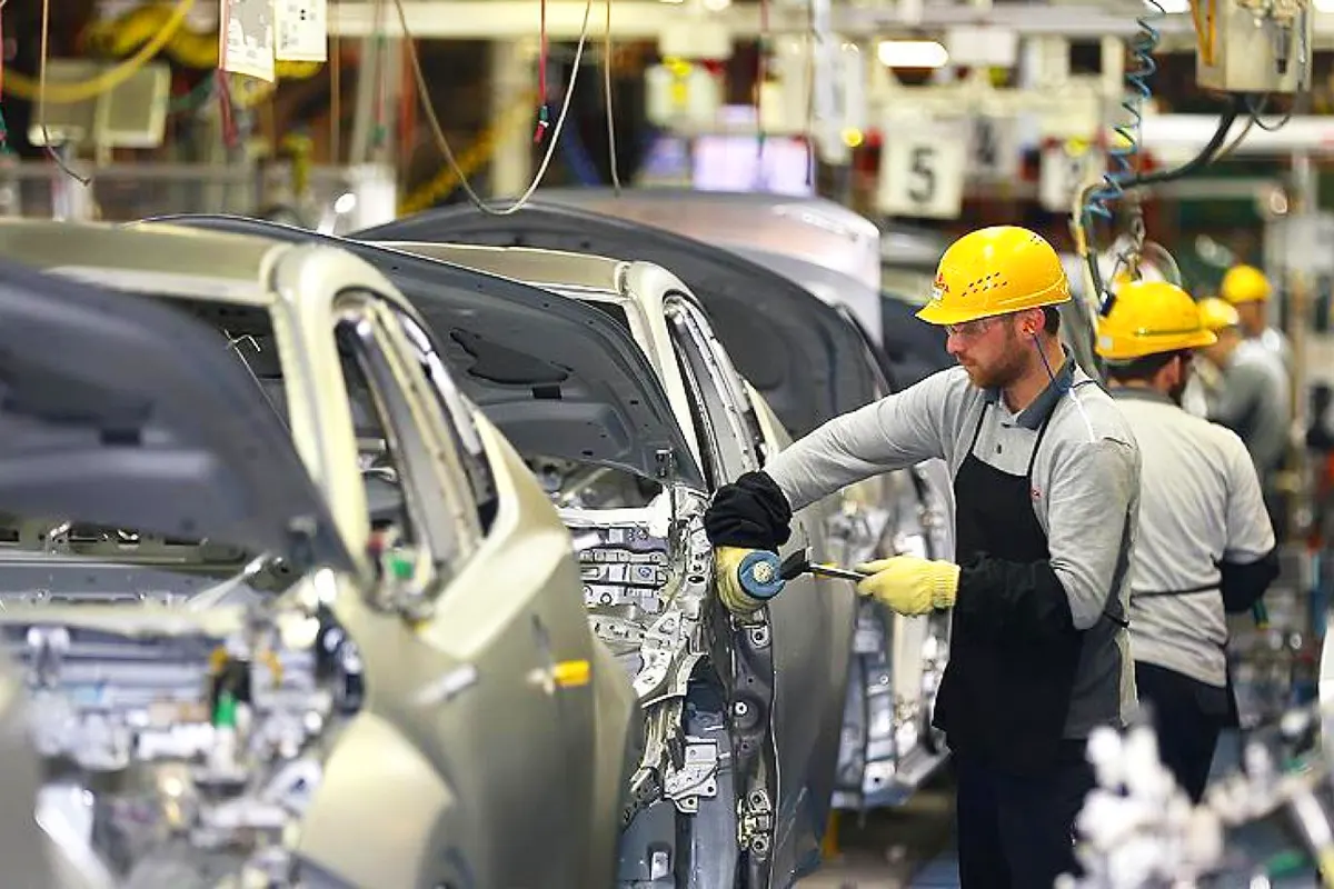 operarios ensamblando coches en una fábrica de automóviles