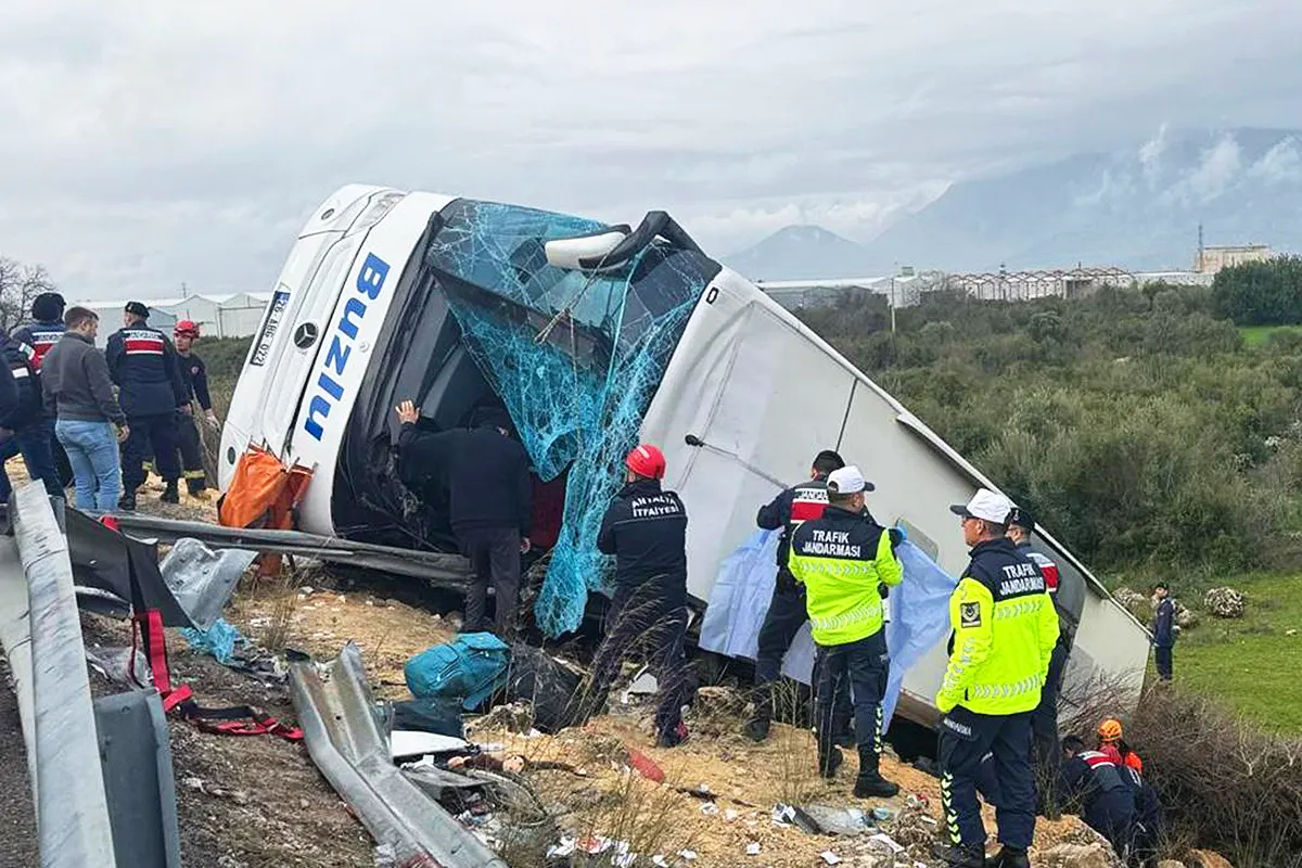 un autobús volcado fuera de la carretera rodeado de equipos de emergencia tras sufrir un accidente en Antalya, Turquía