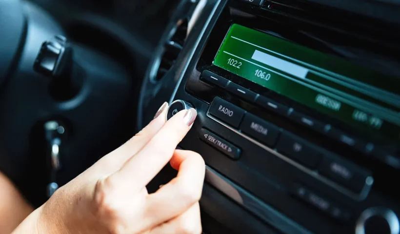 a woman's hand tunes a digital radio in the car