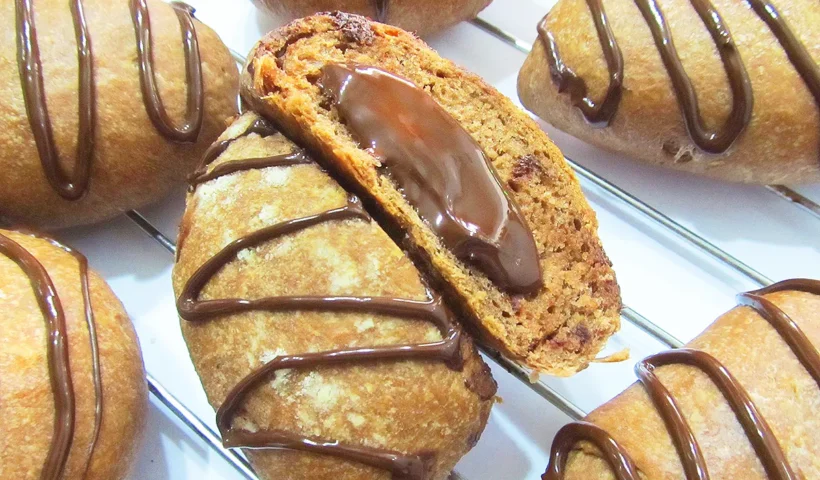 several buns made with flour and cocoa and decorated, one of them split and showing its chocolate filling inside