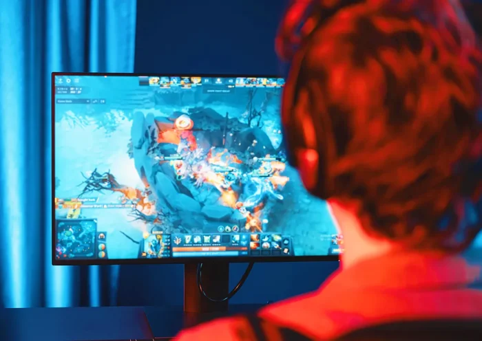 Gaming industry: a young man plays a video game in front of a PC monitor.