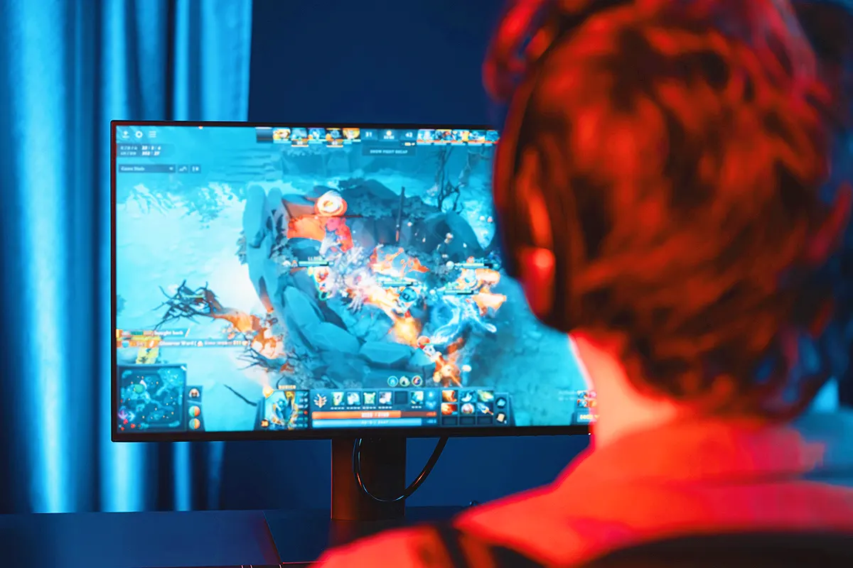 Gaming industry: a young man plays a video game in front of a PC monitor.