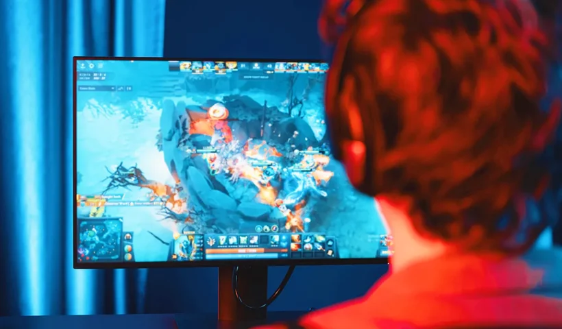 industria del gaming: un joven juega a un videojuego frente a un monitor de PC