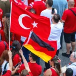 un grupo de personas de origen turco muestran camisetas y banderas de Turquía además de una bandera de Alemania