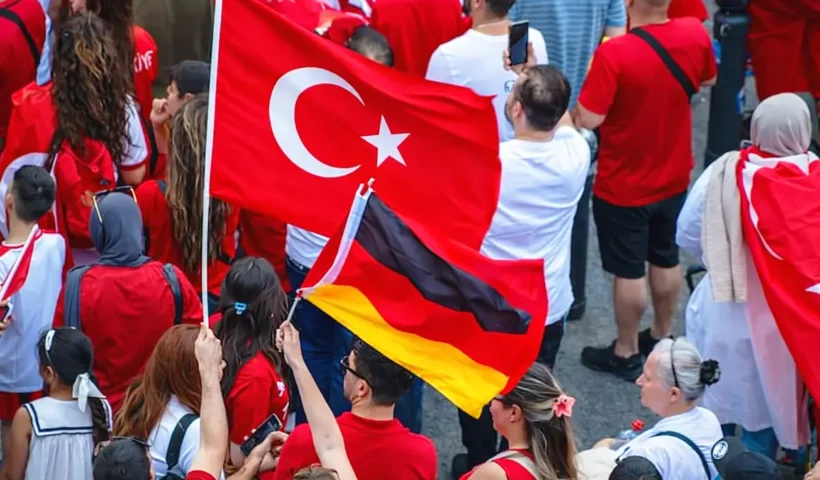 un grupo de personas de origen turco muestran camisetas y banderas de Turquía además de una bandera de Alemania