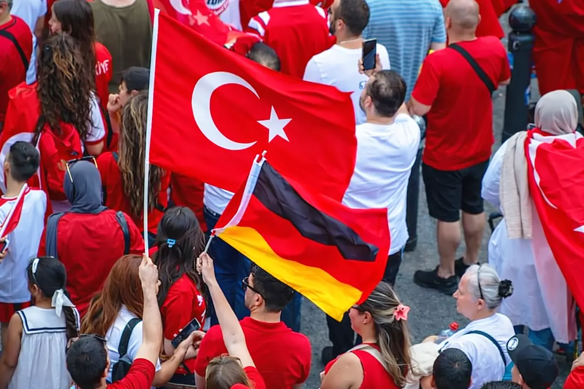 un grupo de personas de origen turco muestran camisetas y banderas de Turquía además de una bandera de Alemania
