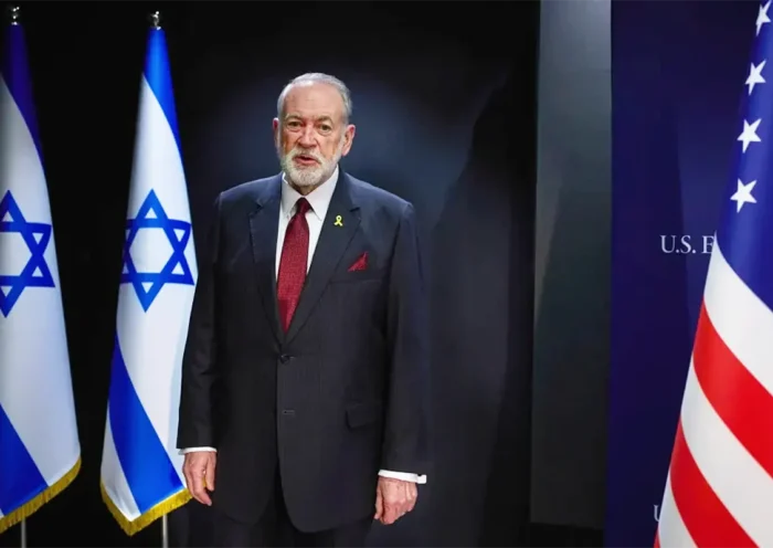 US Ambassador Mike Huckabee next to the Israeli and US flags