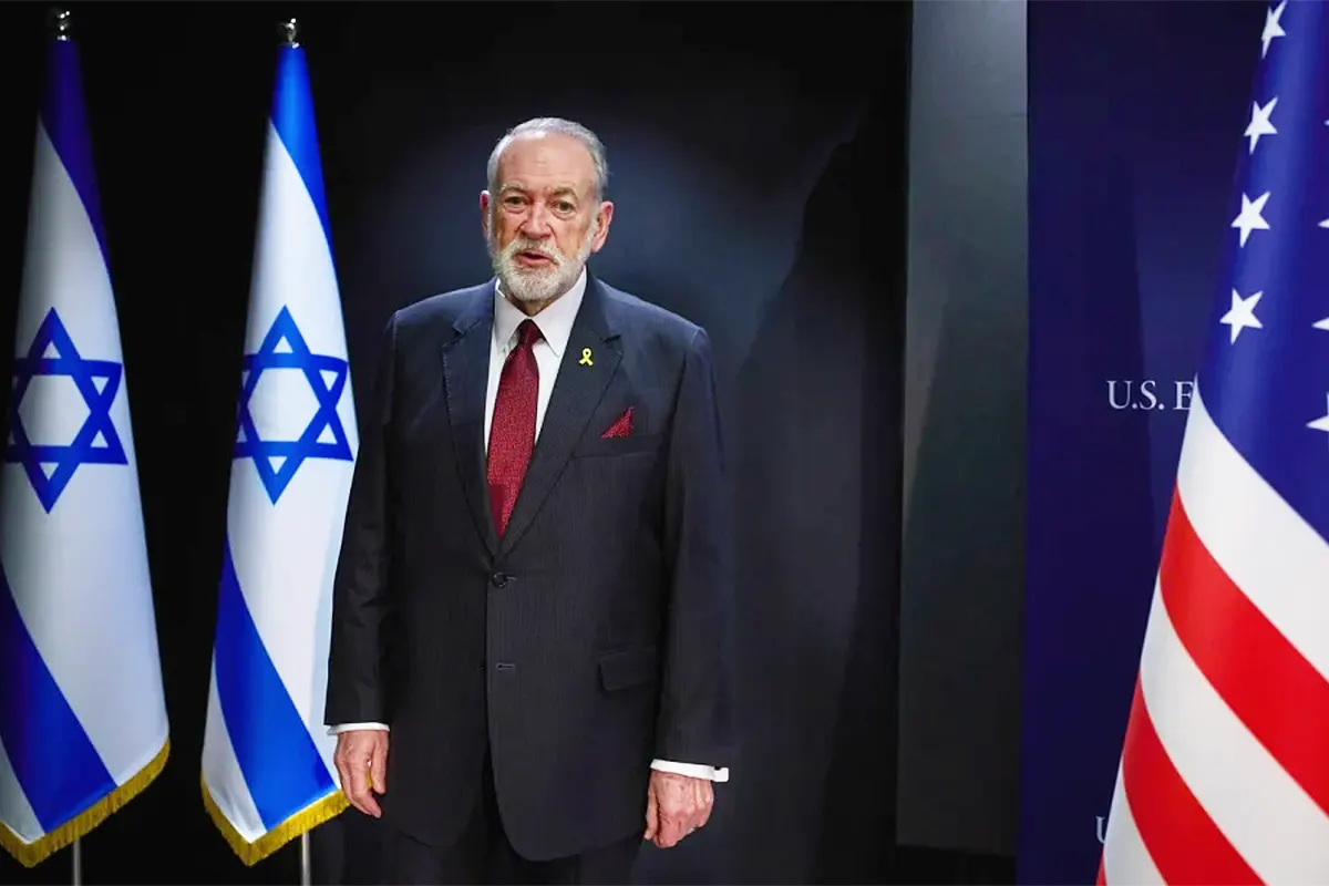 US Ambassador Mike Huckabee next to the Israeli and US flags