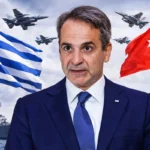 Greek Prime Minister Mitsotakis, in the background the flags of Greece and Turkey with armies of the two countries facing each other.