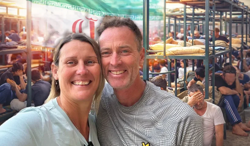 Imagen de la pareja británica Lindsay y Craig Foreman, de fondo el interior de una prisión iraní junto a una bandera de Irán.