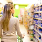 A woman shops and looks at prices in a supermarket.