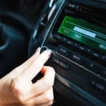 una mano de mujer sintoniza una radio digital en el coche