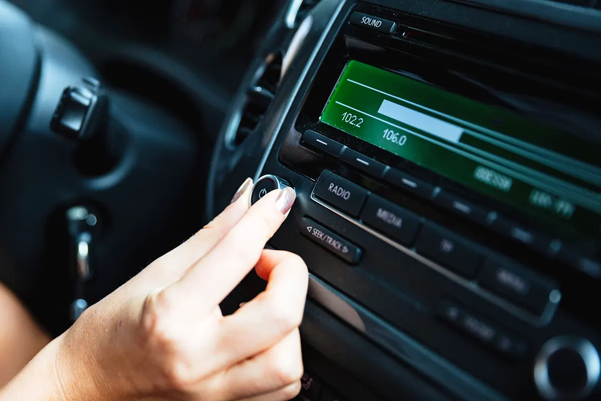 una mano de mujer sintoniza una radio digital en el coche