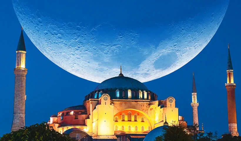 La Gran Mezquita Santa Sofía de Estambul durante el mes sagrado del Ramadán, se muestra iluminada de noche y con una enorme luna decreciente de fondo