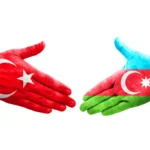a hand painted with the flag of Turkey and a hand painted with the flag of Azerbaijan shake hands