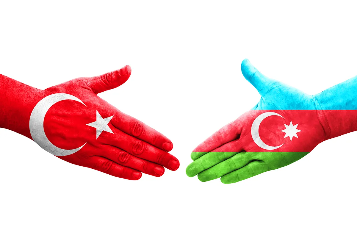 una mano pintada con la bandera de Turquía y otra pintada con la bandera de Azerbaiyán se dan la mano
