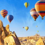 globos aerostáticos de múltiples colores sobrevolando el paisaje de chimeneas de hadas de la Capadocia