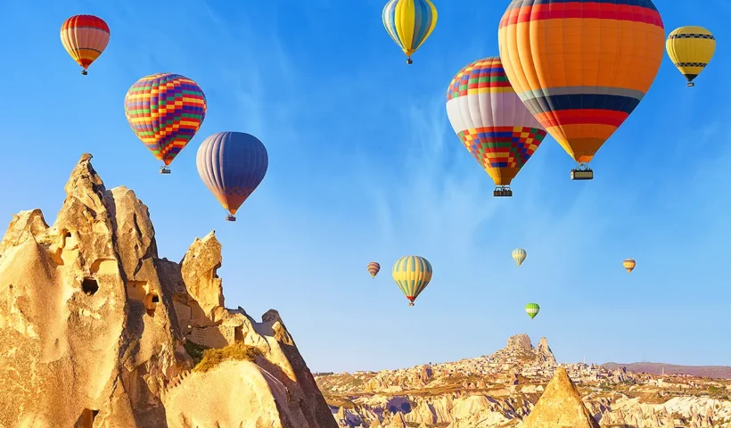 globos aerostáticos de múltiples colores sobrevolando el paisaje de chimeneas de hadas de la Capadocia