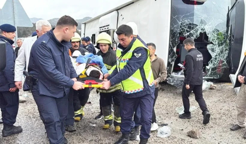 personal de emergencias evacúa en camilla a un herido junto a un autobús volcado sobre la carretera y con los cristales rotos