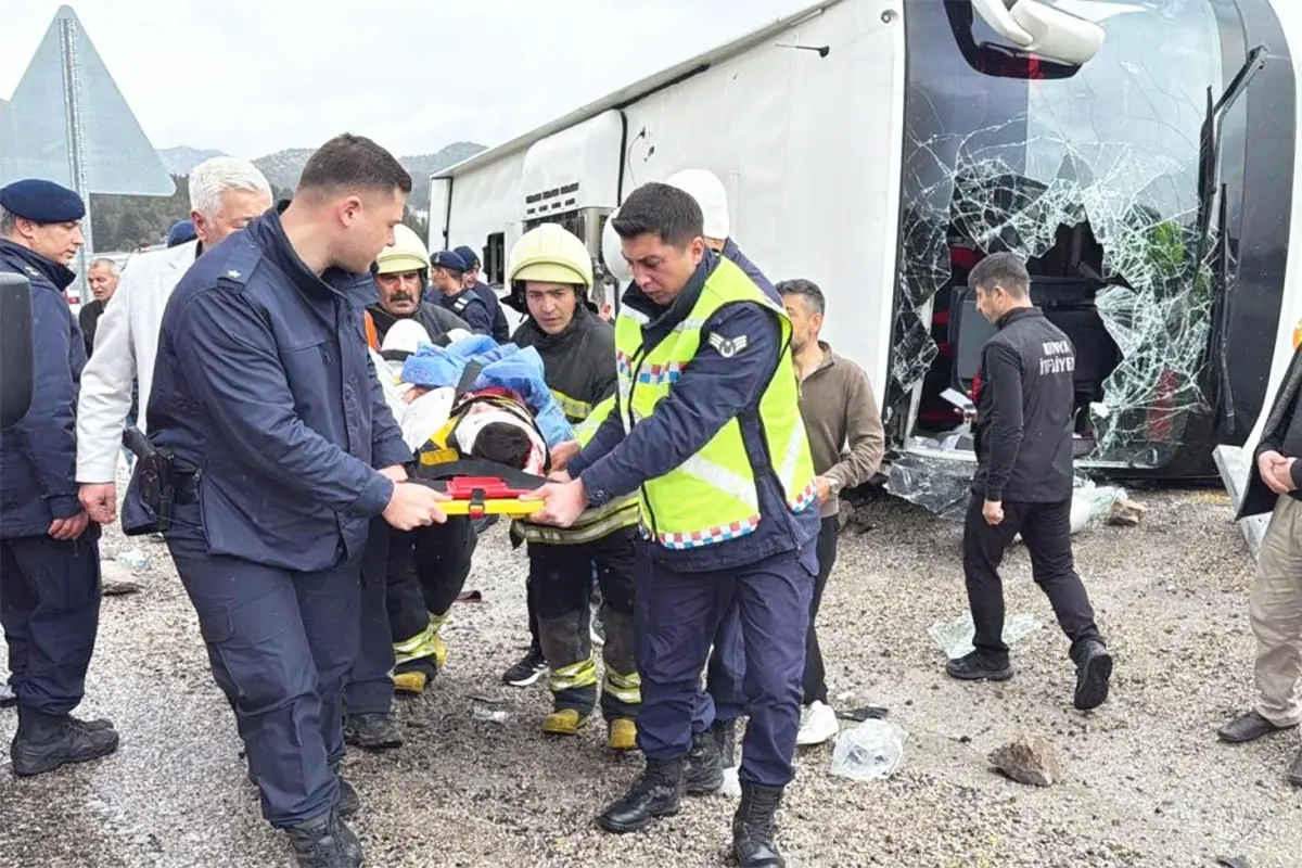 personal de emergencias evacúa en camilla a un herido junto a un autobús volcado sobre la carretera y con los cristales rotos