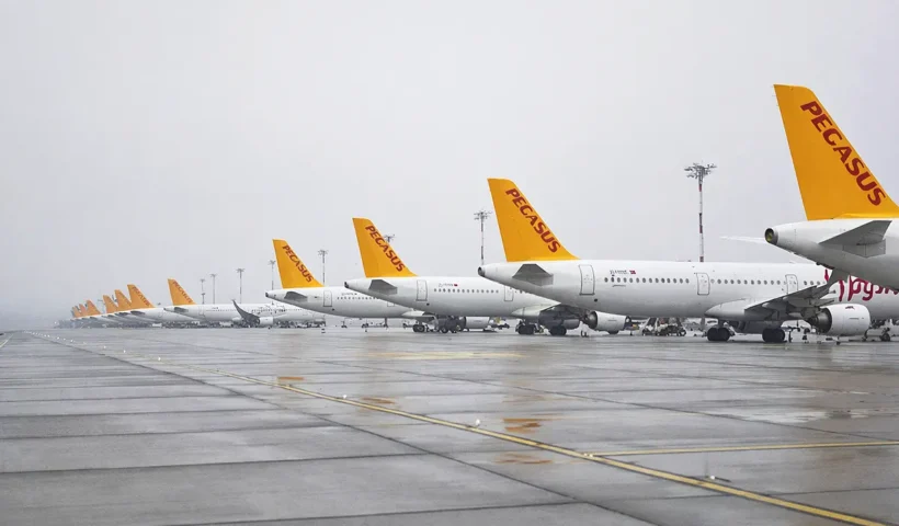 decenas de aviones de la aerolínea Pegasus alineados en la pista de un aeropuerto en medio de un tiempo grisáceo y lluvioso