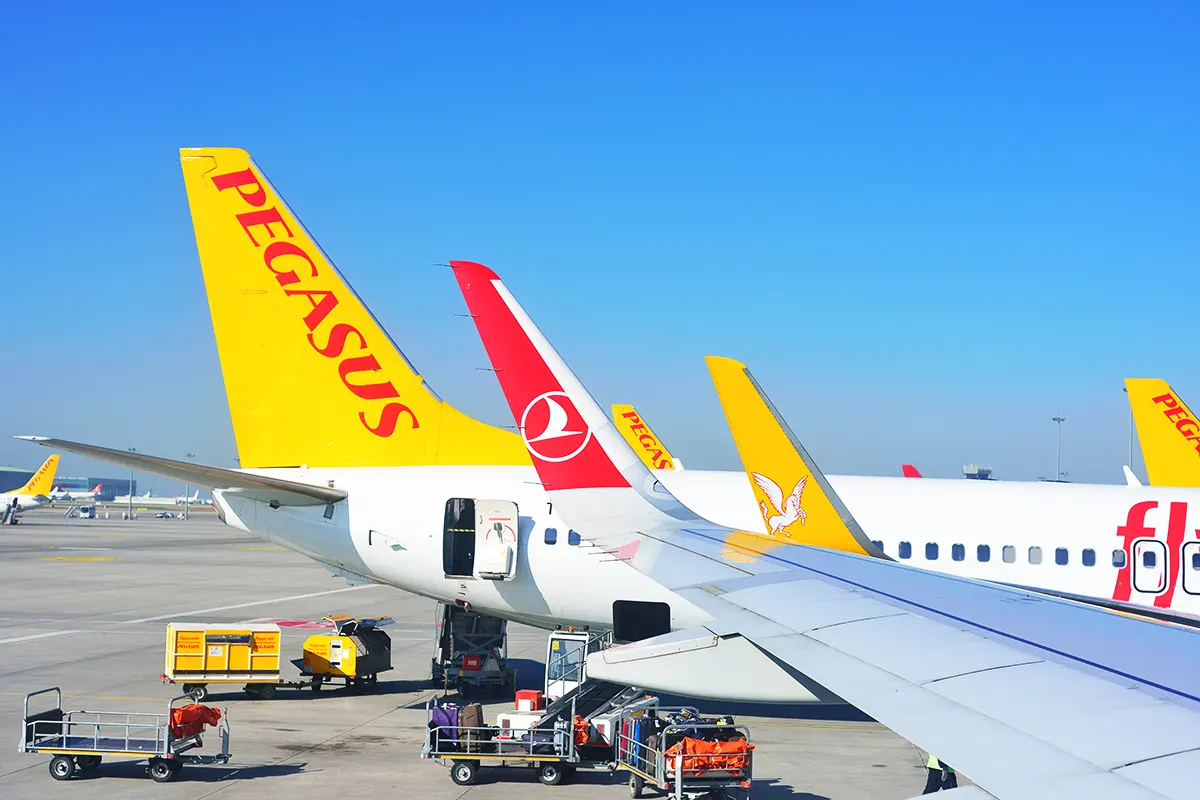 imagen de la pista de un aeropuerto mostrando la cola de un avión de Pegasus y el ala de un avión de Turkish Airlines