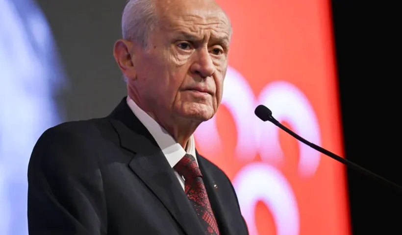 Turkey's nationalist leader, Devlet Bahçeli, next to a nationalist flag with the three crescent moons on a red background.