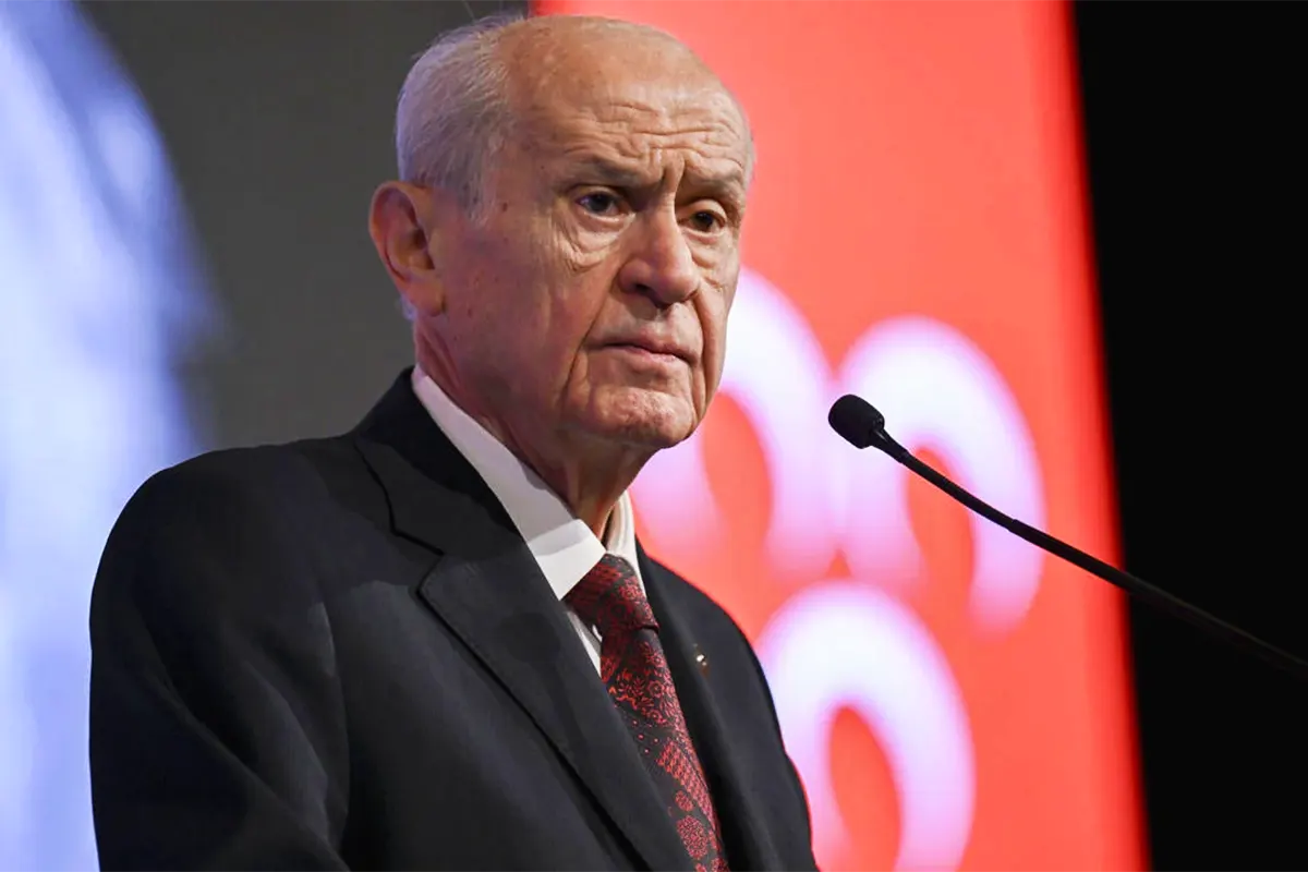 Turkey's nationalist leader, Devlet Bahçeli, next to a nationalist flag with the three crescent moons on a red background.