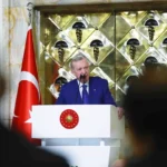 el presidente turco Tayyip Erdoğan pronuncia un discurso ante una audiencia desde un podio, junto a una bandera de Turquía