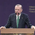 el presidente turco Tayyip Erdoğan habla desde un púlpito con un símbolo del partido AKP de fondo