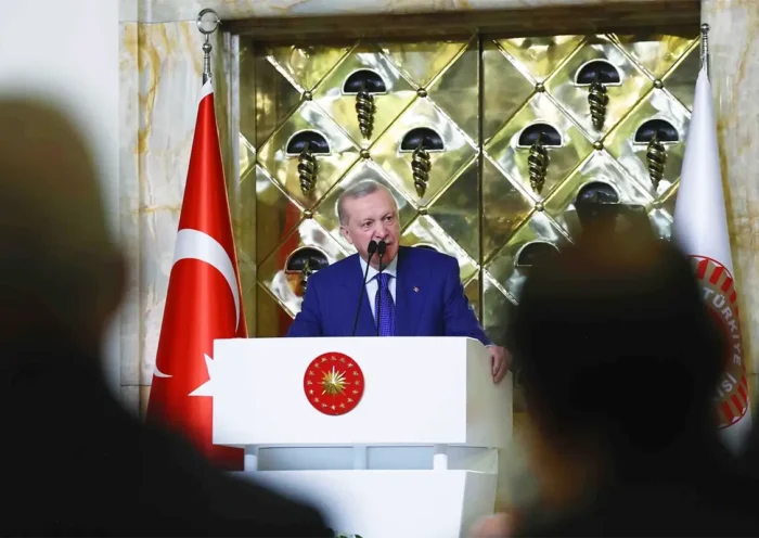 Turkish President Tayyip Erdoğan addresses an audience from a podium, next to a Turkish flag.