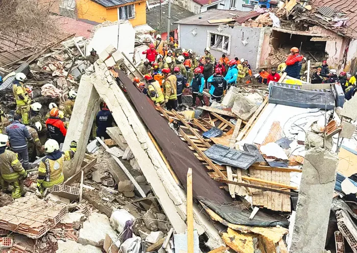dozens of rescue team members work amidst the wreckage of ruined buildings