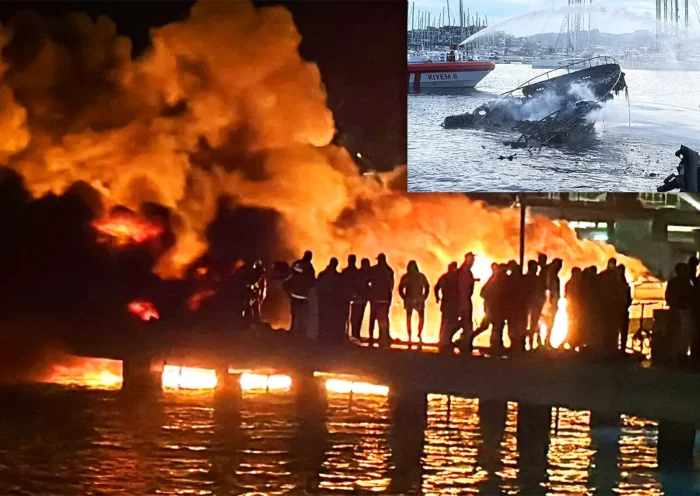 Several people look at a large fire at night in Bodrum marina, in one corner a daytime image of the harbour with a sunken yacht.