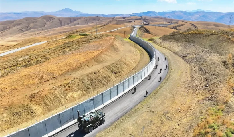 imagen de un amplio paisaje en la frontera entre Irán y Turquía, con un muro fronterizo y patrullas turcas a lo largo del lado turco de la frontera