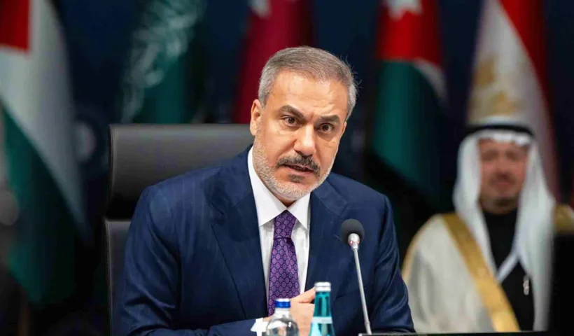 el ministro de exteriores de Turquía, Hakan Fidan, hablando en un foro con varias banderas árabes y líderes árabes de fondo