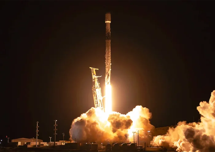un cohete de SpaceX despegando en la noche en medio de una llamarada y una nube de humo