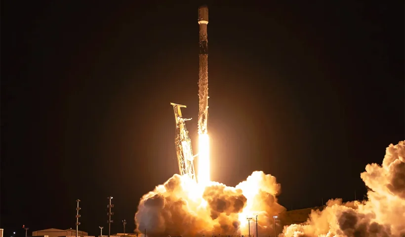 un cohete de SpaceX despegando en la noche en medio de una llamarada y una nube de humo