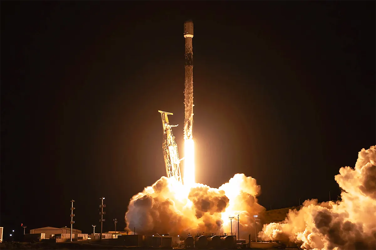 un cohete de SpaceX despegando en la noche en medio de una llamarada y una nube de humo