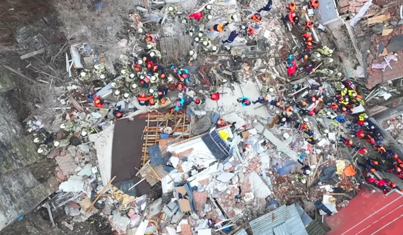 decenas de miembros de equipos de rescate vistos desde el aire mientras trabajan sobre una zona entre varios edificios devastada por una explosión