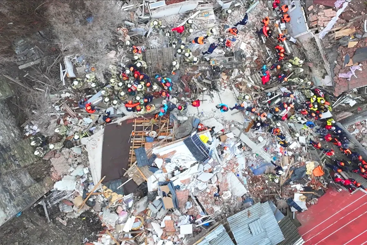 decenas de miembros de equipos de rescate vistos desde el aire mientras trabajan sobre una zona entre varios edificios devastada por una explosión