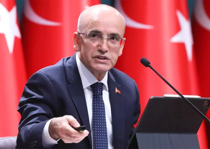 el ministro turco Mehmet Şimşek con varias banderas de Turquía de fondo
