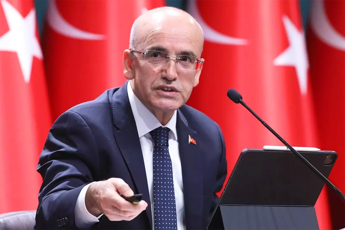 el ministro turco Mehmet Şimşek con varias banderas de Turquía de fondo