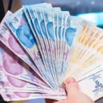 a hand holds a wad of Turkish lira banknotes in a fanned out position