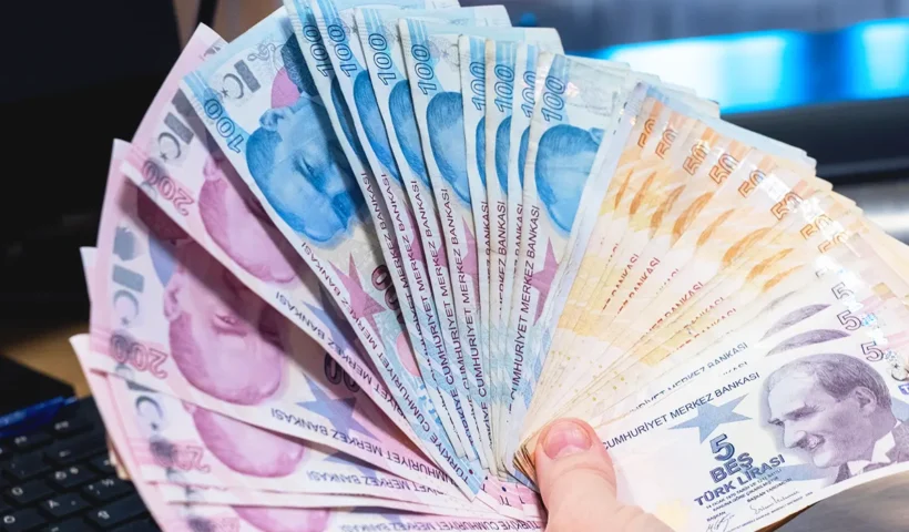 a hand holds a wad of Turkish lira banknotes in a fanned out position