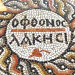 un mosaico romano en forma de círculo con inscripciones en el centro en griego que dicen "revienta envidioso"