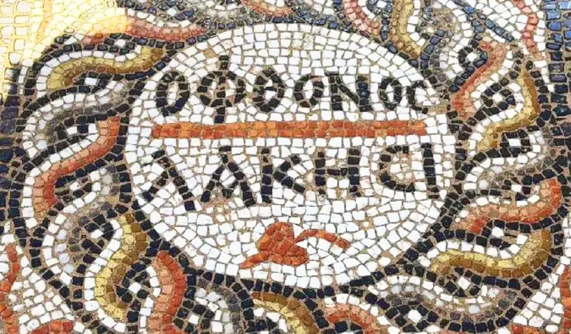 un mosaico romano en forma de círculo con inscripciones en el centro en griego que dicen "revienta envidioso"