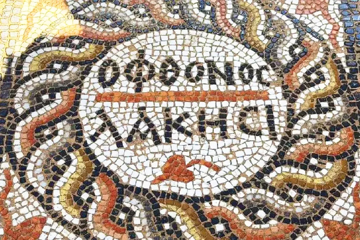 un mosaico romano en forma de círculo con inscripciones en el centro en griego que dicen "revienta envidioso"